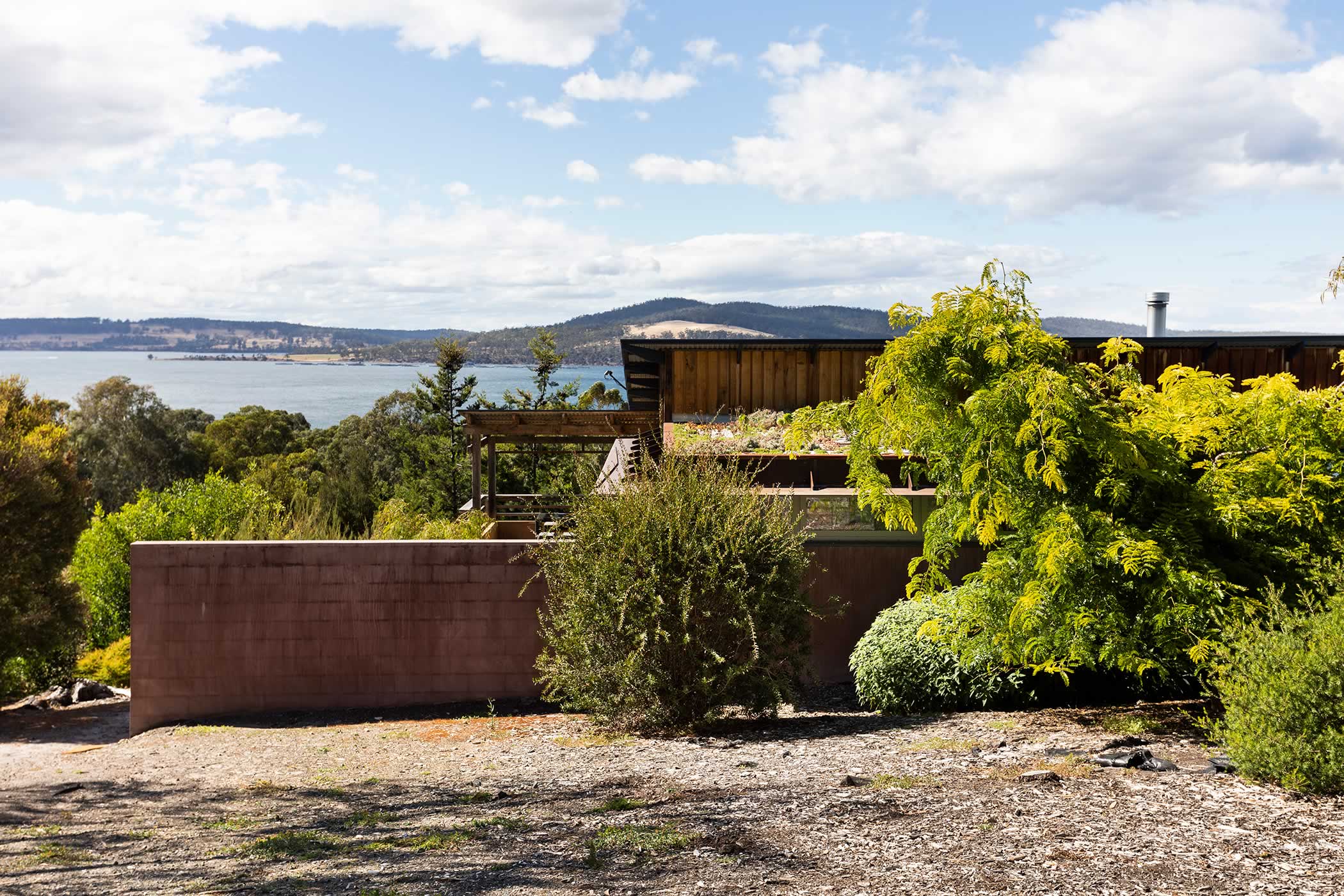 Residential extension, Kettering, Tasmania: The garden studio extension retains the original linear house design set along the contours sympathetic to the horizontal bands of water and the hills beyond. Photo by Adam Gibson.