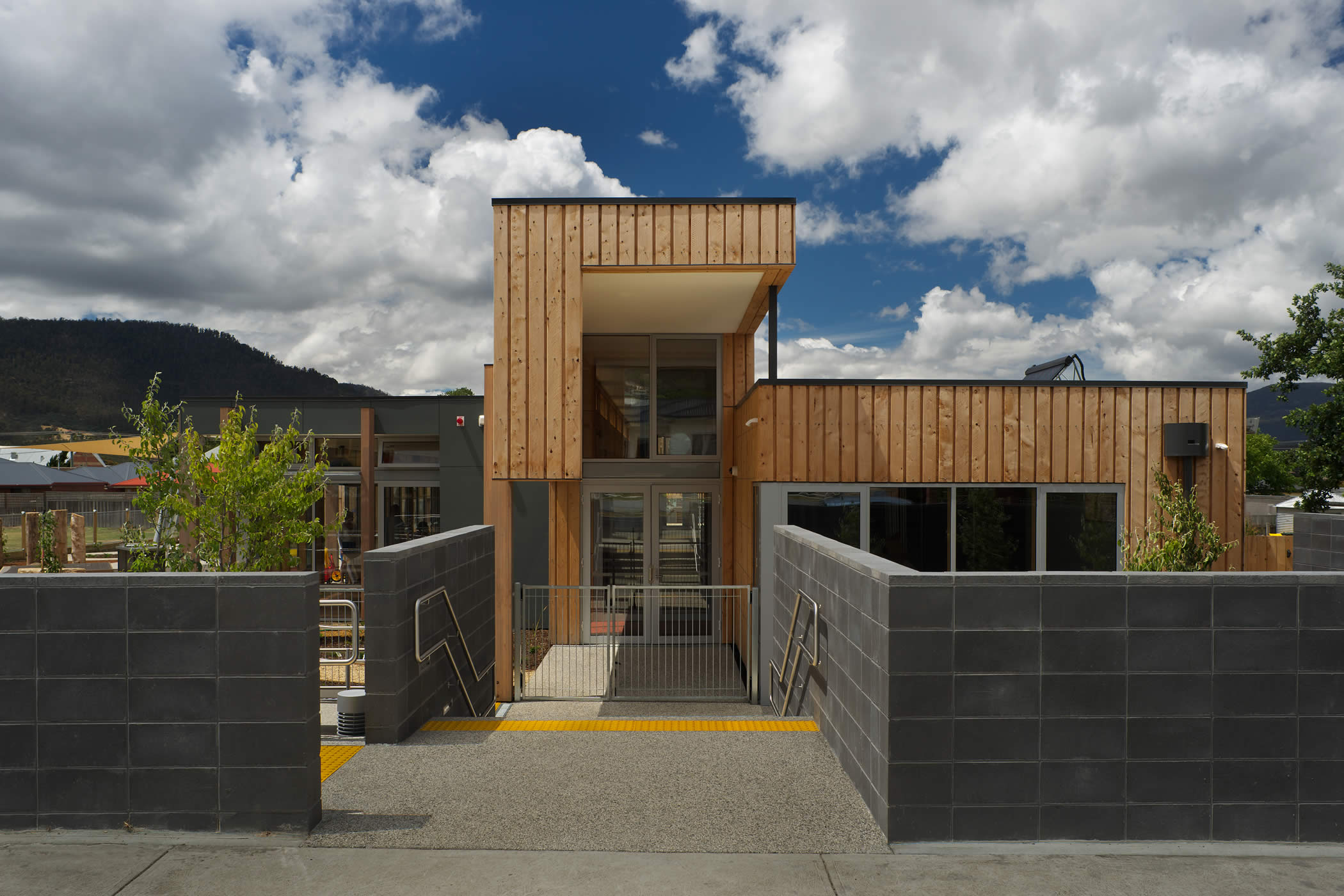 Ptunarra Child and Family Centre, New Norfolk, Tasmania:  The street entrance expresses the interior mezzanine play spine and circulation axis running the building length and introduces the use of external vertical timber cladding. Photo by Ray Joyce.